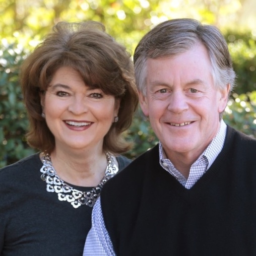 Older couple stand near each other while smiling.