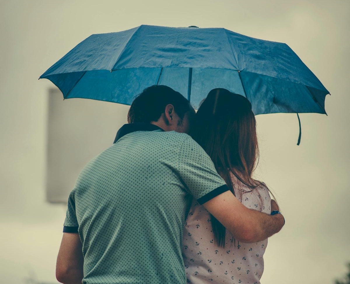 two people huddling under an umbrella