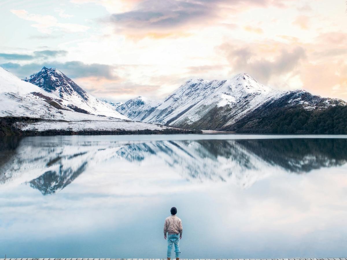 photo of a man looking over a lake towards the mountains