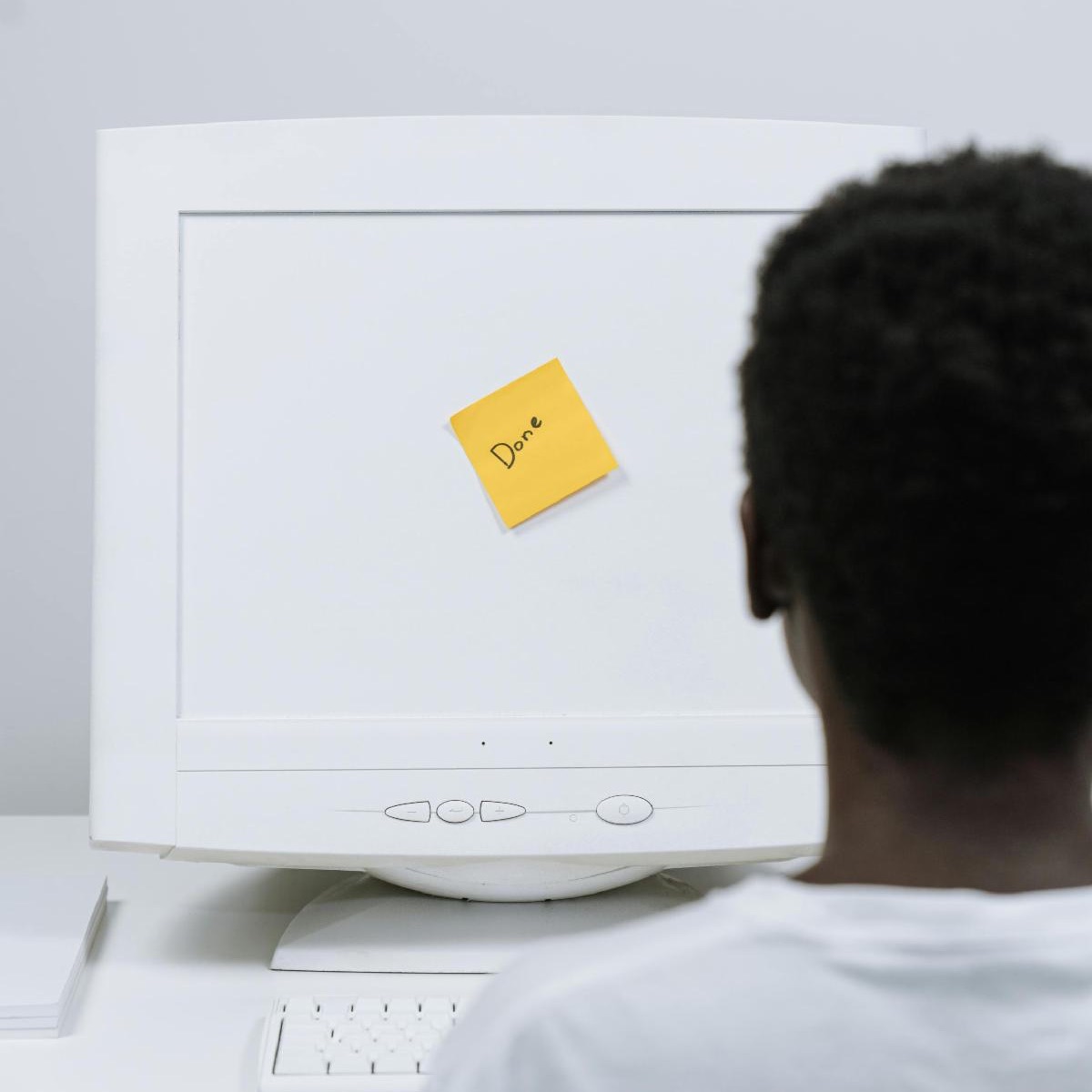 man looking at a computer with a post it on the screen that says, "done"