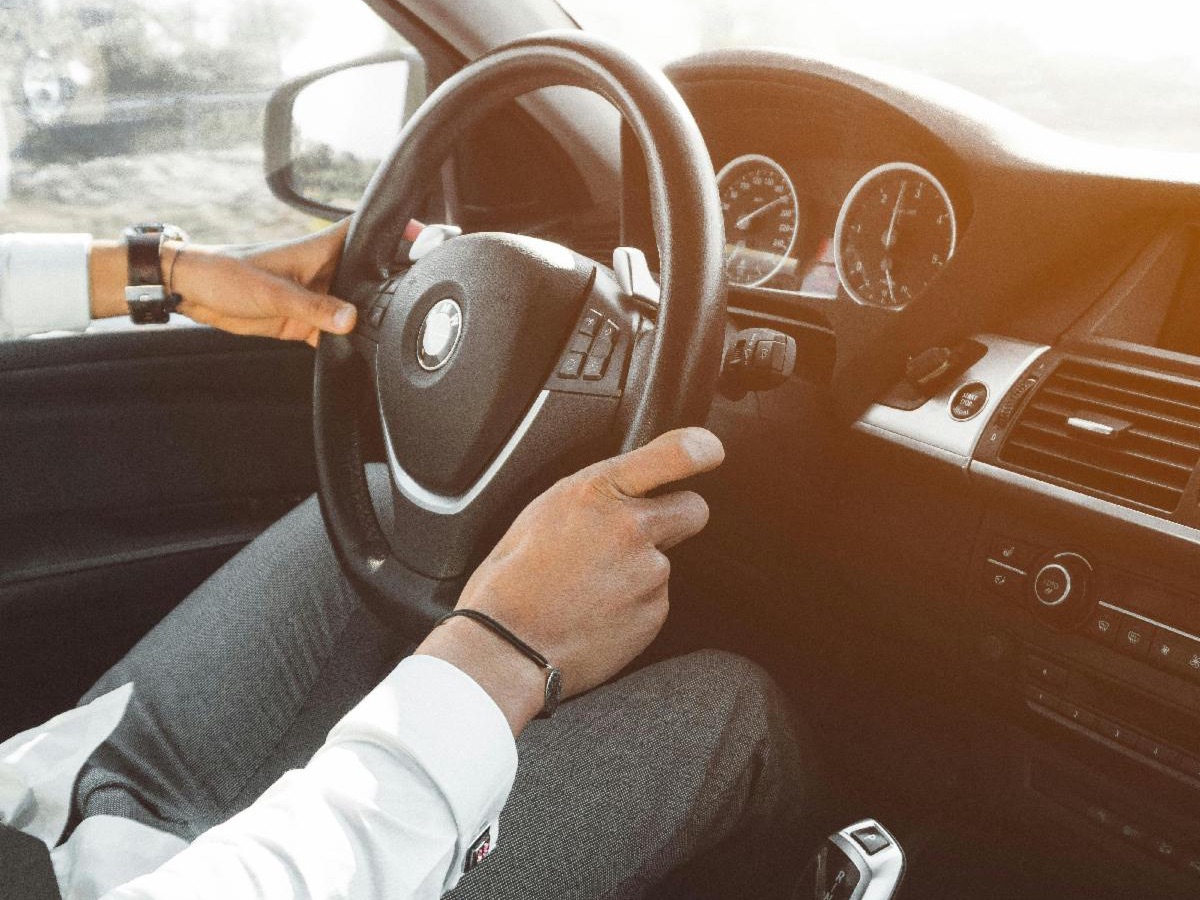 person with their hands on the steering wheel of a car