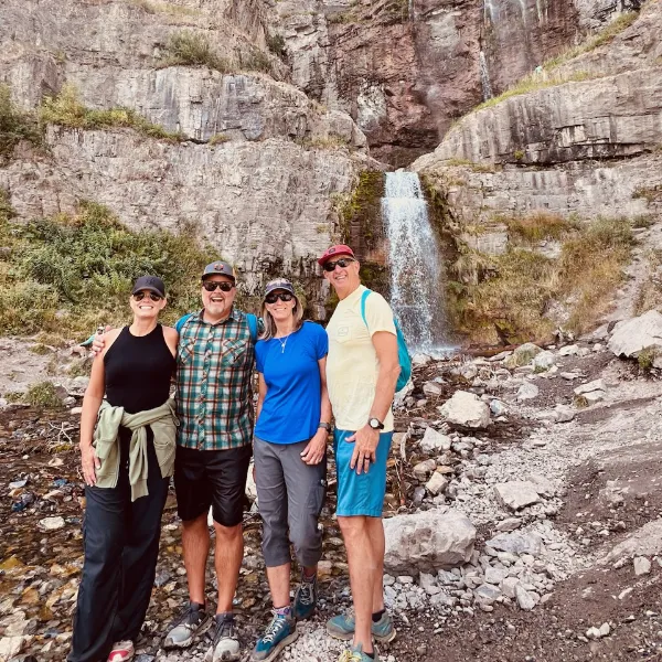 photo of two men and two women standing in front of a waterfall.